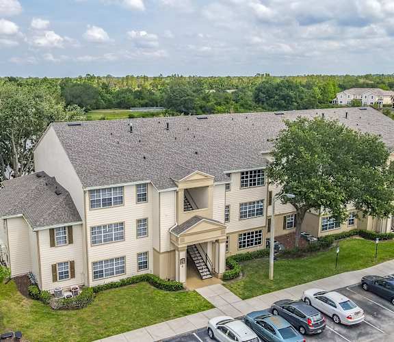 an aerial view of a large apartment building with a parking lot in the foreground