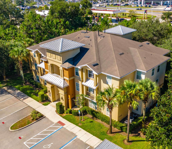 an aerial view of a building with palm trees and parking lot