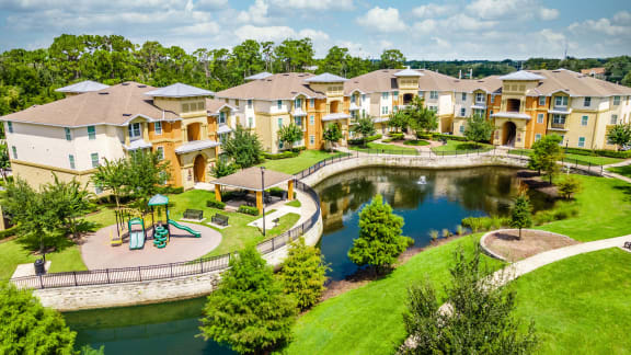 an aerial view of a park with a pond and apartments