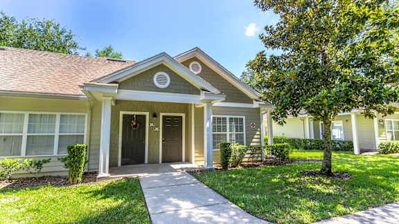 a home with a sidewalk in front of it and a tree