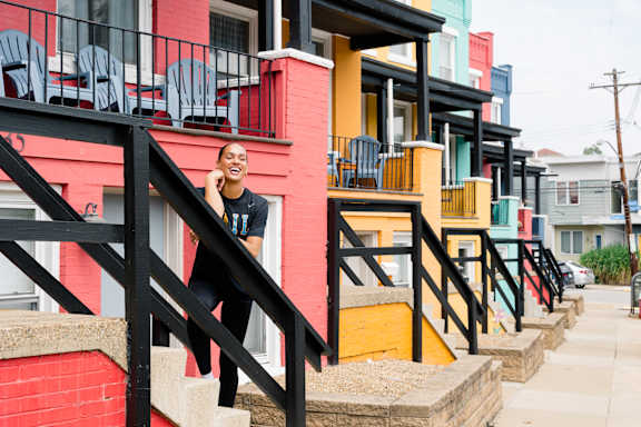 A woman is standing on a staircase in front of a row of colorful houses.