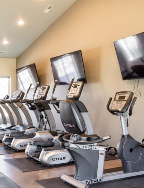 a row of treadmills and televisions in a gym