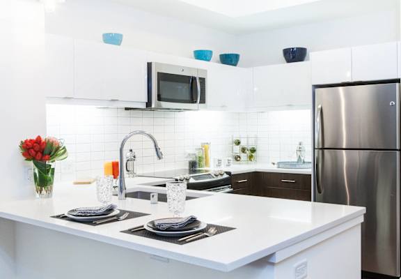 A modern kitchen with a white countertop and stainless steel appliances.