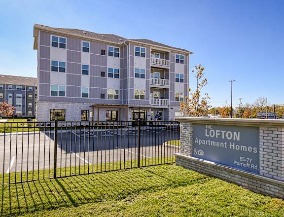 A sign for the Lofton Apartment Homes is in front of a building.