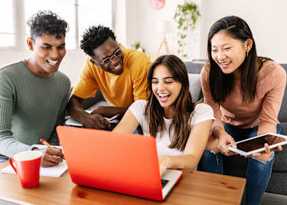 a group of people sitting around a laptop