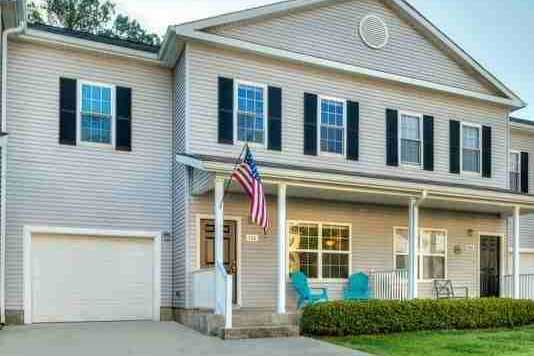 A house with a garage and an American flag hanging on the front door.