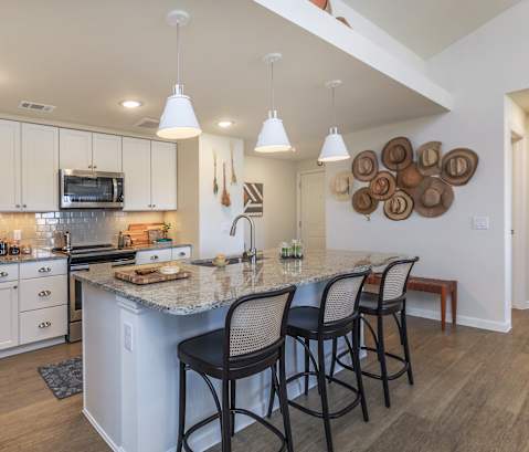 a kitchen with white cabinets and a large island with a granite countertop