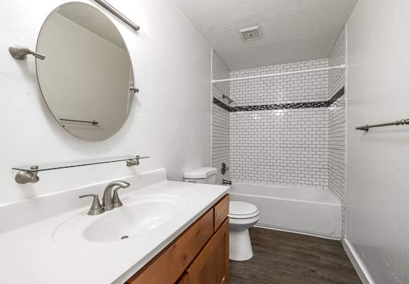A white sink with a round mirror above it.