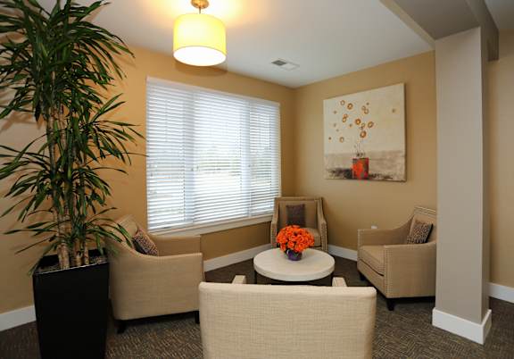 A living room with a large painting on the wall and a potted plant on the left.