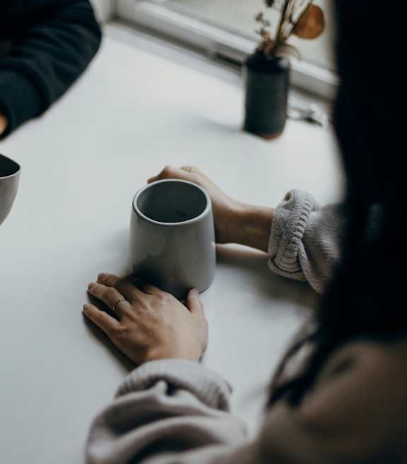 Three hands holding cups of coffee with latte art on top.
