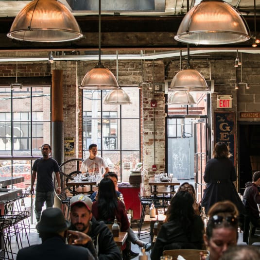 people sitting at tables in a restaurant with large windows