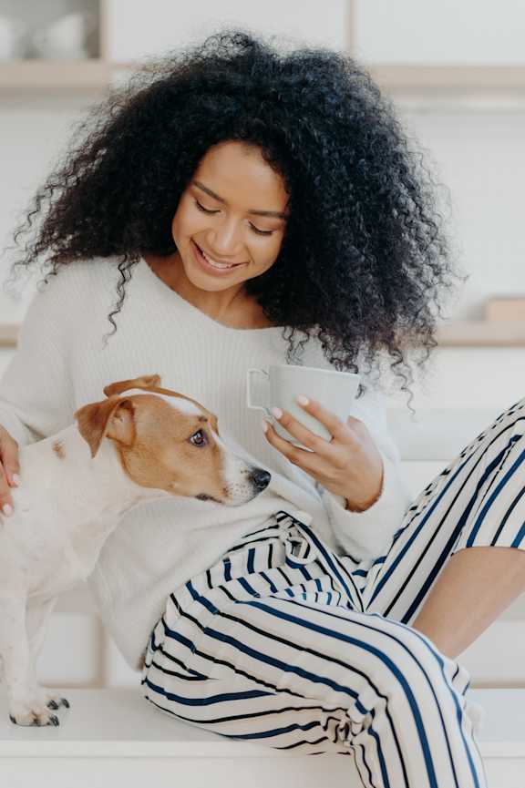 A woman is sitting on a white chair with a white dog on her lap.