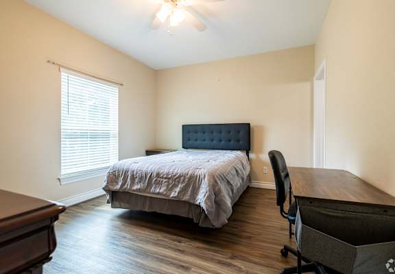 a bedroom with a bed and a desk and a window