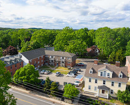 an aerial view of a brick apartment complex with trees in the background
