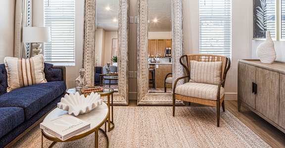 A living room with a sofa, a chair, a coffee table, and two mirrors.