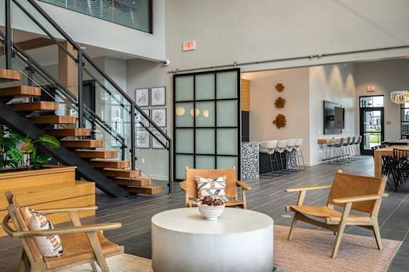 a living room with chairs and a table and a staircase