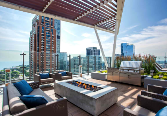 a patio with a fire pit and a grill on top of a building