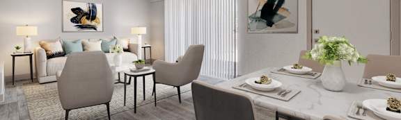 A dining room with a table set for two and a couch with a blue pillow.
