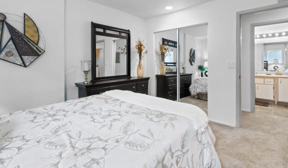 a white bedroom with a bed and a mirror