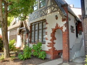 the front of a brick house with a door and a tree