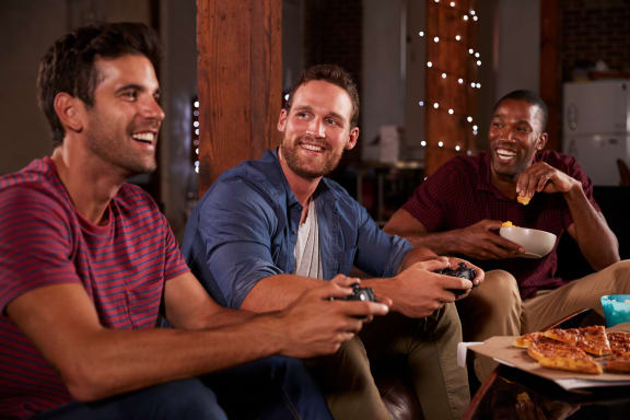 three men sitting on a couch playing video games