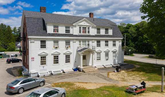 a large white house with a gray roof on a sunny day