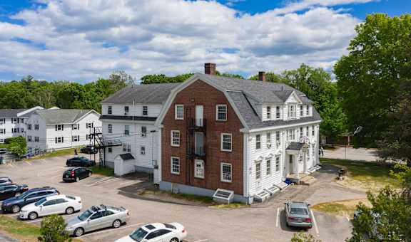 an aerial view of a large red brick building with white trim and a gray roof