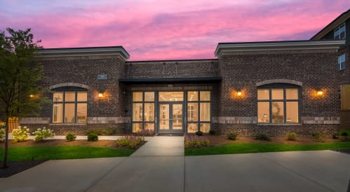 a rendering of a brick building with large windows and a pink sunset in the background