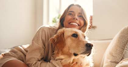 A woman is sitting on a couch holding a dog.