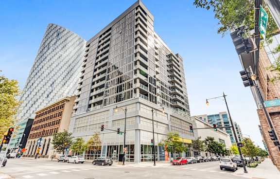 A modern glass building stands in the middle of a busy intersection.