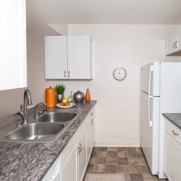 A kitchen with white cabinets and a clock on the wall.