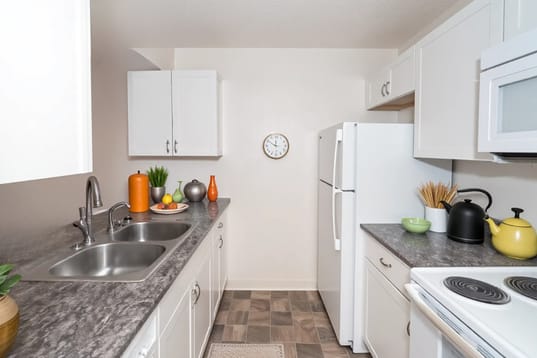A kitchen with white cabinets and a clock on the wall.
