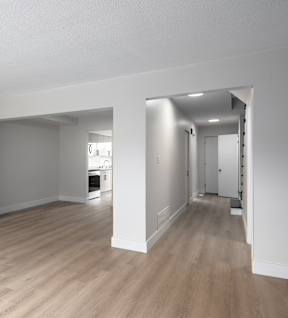 an empty living room and hallway with wood floors and white walls