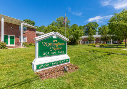 a green and white sign in front of a brick building at Nottingham Manor Apartments, Montvale, New Jersey