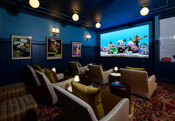 A room with a blue wall and a screen showing a cartoon.