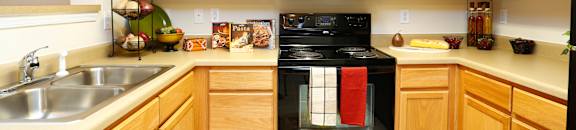 A kitchen with wooden cabinets and a black oven.