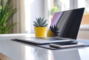 a laptop computer sitting on a table next to a cell phone