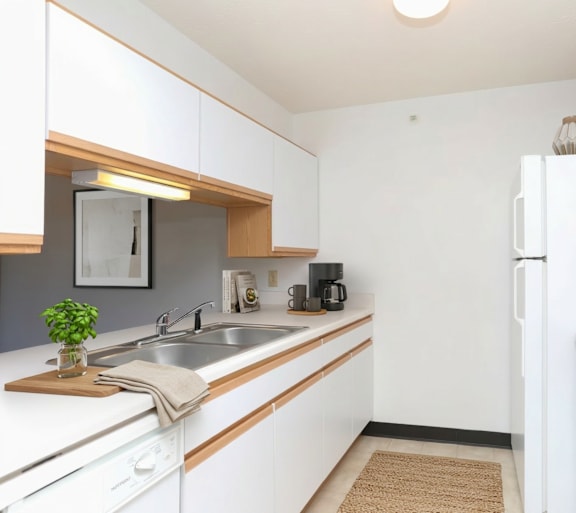 A kitchen with white cabinets and a white fridge.