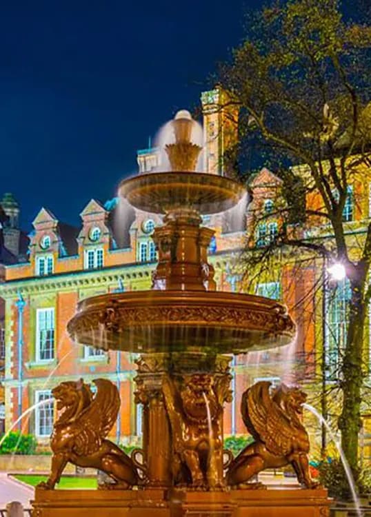 a fountain in front of a large building at night