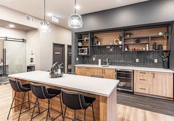 A modern kitchen with a white countertop and black chairs.
