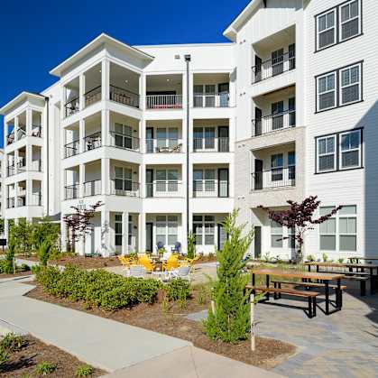 an exterior view of an apartment building with benches and a courtyard at The Eddy at Riverview, Smyrna, GA