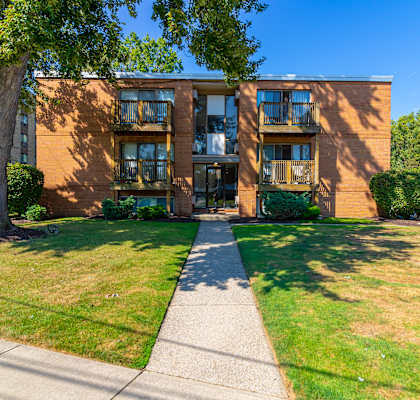a brick apartment building with a sidewalk in front of it