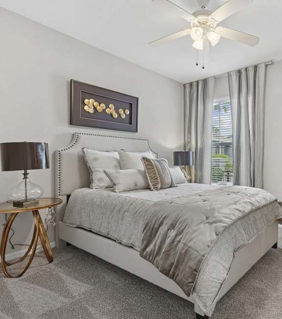 A bedroom with a bed, desk, chair, and mirror.