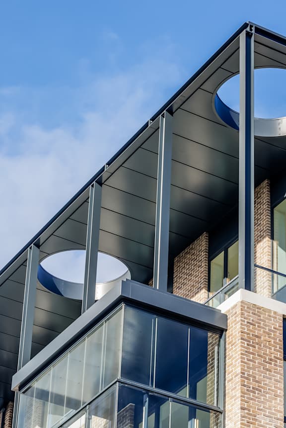 A modern building with a curved glass structure on the upper floor.