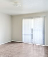 A room with a window covered by white blinds.