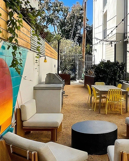 A patio with a table and chairs and a mural on the wall.