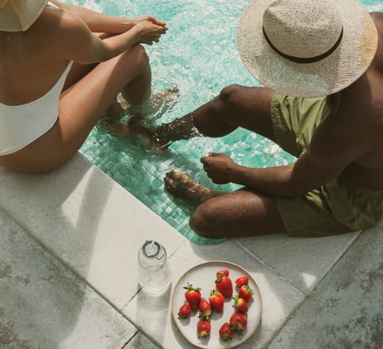 a man and a woman sitting by a pool with their feet in the water