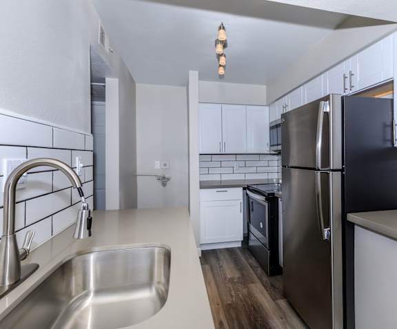 an empty kitchen with stainless steel appliances and white cabinets