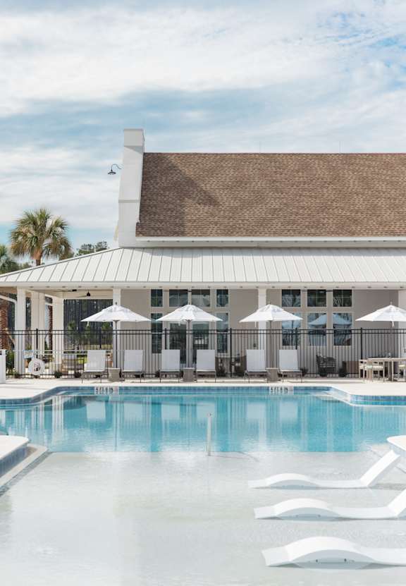 a swimming pool with chaise lounge chairs and a pool house in the background at Saltaire Apartment Homes, Florida, 32459