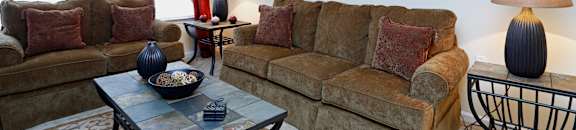A living room with a couch, a coffee table, and a side table with a lamp.
